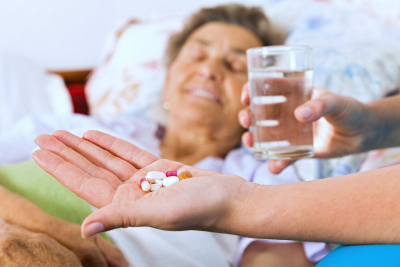 elderly woman taking pills with glass of water